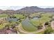 Aerial view showcases the community golf course featuring a scenic lake, lush greens, and mountain views at 4651 N 204Th Ave, Buckeye, AZ 85396