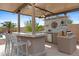 Outdoor kitchen features bar seating, built-in BBQ and a mini fridge at 4651 N 204Th Ave, Buckeye, AZ 85396