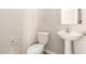 Clean half-bathroom features a pedestal sink, toilet, and a minimalist design at 5430 W Odeum Ln, Phoenix, AZ 85043