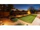 Lush backyard with artificial turf, charming landscaping, and ambient lighting at 5921 E Ocupado Dr, Cave Creek, AZ 85331