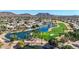 A beautiful aerial view of a lakeside community featuring a golf course, palm trees, and mountain views at 6401 W Irma Ln, Glendale, AZ 85308