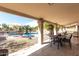 Relaxing covered patio area with dining and views of the fenced pool and desert landscaping at 6401 W Irma Ln, Glendale, AZ 85308