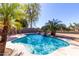 Sparkling blue pool with rock waterfall feature, surrounded by desert landscaping and palm trees at 6401 W Irma Ln, Glendale, AZ 85308