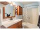 Updated bathroom with wood vanity, shower-tub combo, and blue walls at 8355 E Thomas Rd, Scottsdale, AZ 85251