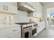 Modern kitchen features stainless steel range hood, gas range, white cabinetry, and tile backsplash at 9370 E Wethersfield Rd, Scottsdale, AZ 85260