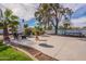 Expansive backyard featuring a concrete patio, lush palms, a swing set, and a basketball court at 99 W Circle Dr, Florence, AZ 85132