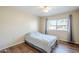 Bedroom with a ceiling fan, neutral walls, wood-look flooring, and large window with neighborhood views at 10407 W Mission Ln, Sun City, AZ 85351