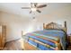 Bedroom with wood floors, ceiling fan, a large bed with a colorful blanket and wooden furniture at 10407 W Mission Ln, Sun City, AZ 85351