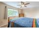 Bedroom with wood floors, ceiling fan, a large window with tree views and a bed with a colorful blanket at 10407 W Mission Ln, Sun City, AZ 85351