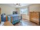 Bedroom with wood floors, ceiling fan, a large window, dresser and bed with a colorful blanket at 10407 W Mission Ln, Sun City, AZ 85351