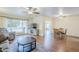 Open-concept living room with hardwood floors, fan, and large window, seamlessly connected to the dining area at 10407 W Mission Ln, Sun City, AZ 85351