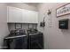 Modern laundry room with black front-loading washer and dryer, white cabinets, and decor at 1236 E Silver Reef Dr, Casa Grande, AZ 85122