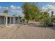 Expansive backyard with low-maintenance gravel landscaping, mature trees, and a quaint bridge feature at 12408 N Cherry Hills W Dr, Sun City, AZ 85351