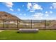 Backyard with artificial grass, fire pit, mountain views, and black wrought iron fence at 13763 N Campsite Ct, Fountain Hills, AZ 85268