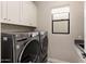 Bright laundry room featuring updated washer and dryer with upper cabinet storage and window at 13763 N Campsite Ct, Fountain Hills, AZ 85268