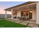 Back patio with a dining table and landscaped backyard featuring pavers and artificial grass at 15667 W Mercer Ln, Surprise, AZ 85379