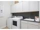 Clean laundry room featuring black backsplash, white cabinets, and modern washer and dryer at 15667 W Mercer Ln, Surprise, AZ 85379