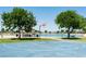 Outdoor basketball court with blue surface near a pond and picnic area with mature trees and green grass at 15683 W Mercer Ln, Surprise, AZ 85379