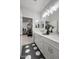 Bathroom with double sinks, white countertops, black and white patterned flooring, and bedroom view at 15683 W Mercer Ln, Surprise, AZ 85379