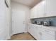 Convenient laundry room with ample white cabinets, countertop space, and tiled backsplash at 15683 W Mercer Ln, Surprise, AZ 85379