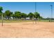 Sandy volleyball court surrounded by a green field, set with a net and located near a park at 15683 W Mercer Ln, Surprise, AZ 85379