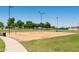 Sandy volleyball court with a green grass border, set with a new net and surrounded by trees at 15683 W Mercer Ln, Surprise, AZ 85379