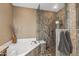 Bathroom featuring a soaking tub, walk-in shower with rock floor, neutral paint, and designer touches at 15701 W Huron Dr, Sun City West, AZ 85375