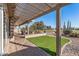 Inviting covered patio overlooking a green lawn and golf course with desert landscaping and comfortable seating at 15701 W Huron Dr, Sun City West, AZ 85375