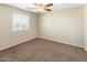 Cozy bedroom featuring a ceiling fan and a sunlit window with neutral walls and carpet at 1655 W Wilson Ave, Coolidge, AZ 85128