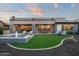 Backyard featuring outdoor seating, a small water feature, green turf, and a covered patio with outdoor dining area at 18024 E Wolf Tree Ln, Rio Verde, AZ 85263