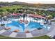 Aerial view of a community pool area with lounge chairs, umbrellas, cabanas, and palm trees at 18024 E Wolf Tree Ln, Rio Verde, AZ 85263