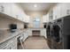 Well-lit laundry room offers dual washer-dryers, workspace, storage, and sleek design in a functional space at 18024 E Wolf Tree Ln, Rio Verde, AZ 85263