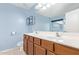 Bathroom featuring a double sink vanity with wood cabinets and framed mirror and blue walls at 2021 S 84Th Ave, Tolleson, AZ 85353