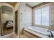 Bathroom featuring a bathtub, tile surround, window, and access to shower and bedroom at 20704 N 90Th Pl # 1065, Scottsdale, AZ 85255