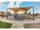 Community playground with covered play structures, sandy ground cover, and sidewalk access on a sunny day at 21629 N Dietz Dr, Maricopa, AZ 85138