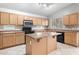 Well-lit kitchen with an island, black appliances, and lots of cabinet space at 24118 W Desert Bloom St, Buckeye, AZ 85326