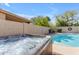 Backyard featuring a hot tub adjacent to a pool with lush greenery and privacy fencing at 2419 E Goldenrod St, Phoenix, AZ 85048