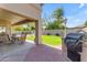 Spacious backyard with a covered patio, built-in grill, green lawn and pool in the distance at 2419 E Goldenrod St, Phoenix, AZ 85048