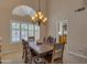 The dining room features a wooden table, six chairs, and a stylish chandelier. The window overlooks the pool area at 2419 E Goldenrod St, Phoenix, AZ 85048