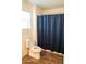 Bright bathroom features a toilet, shower with blue curtain, and window at 27 N 199Th Ave, Buckeye, AZ 85326