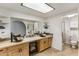 Bathroom featuring dual sinks with wooden cabinets and a bright skylight above at 301 E Carol Ann Way, Phoenix, AZ 85022