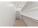 A well-lit walk-in closet featuring shelving, rod for hanging clothes and neutral colored carpeting at 37582 W San Clemente St, Maricopa, AZ 85138