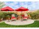 Charming backyard patio area with two lounge chairs, red umbrellas, and beautiful landscaping at 3932 E Torrey Pines Ln, Chandler, AZ 85249