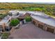 Stunning aerial view of a luxury estate showcasing the tile roof, brick driveway, desert landscaping, and surrounding mountain vistas at 41731 N Stone Cutter Dr, Scottsdale, AZ 85262