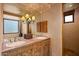 Bathroom with double sinks, stone countertops, rustic wood cabinetry, and stylish light fixtures at 41731 N Stone Cutter Dr, Scottsdale, AZ 85262