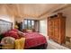 Spacious bedroom with a large window offering desert views and a large wooden wardrobe at 41731 N Stone Cutter Dr, Scottsdale, AZ 85262