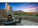 This outdoor living space includes a fireplace and seating with views of the desert landscape at 41731 N Stone Cutter Dr, Scottsdale, AZ 85262