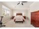 Spacious bedroom with ceiling fan, carpet flooring, large window, and elegant dark wood furniture at 5356 W Jupiter Way, Chandler, AZ 85226