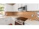 Kitchen features white cabinets, a stainless steel stove, and a multicolored tile backsplash at 5356 W Jupiter Way, Chandler, AZ 85226