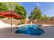 Inviting backyard pool with mature trees and an orange umbrella for shade at 5356 W Jupiter Way, Chandler, AZ 85226